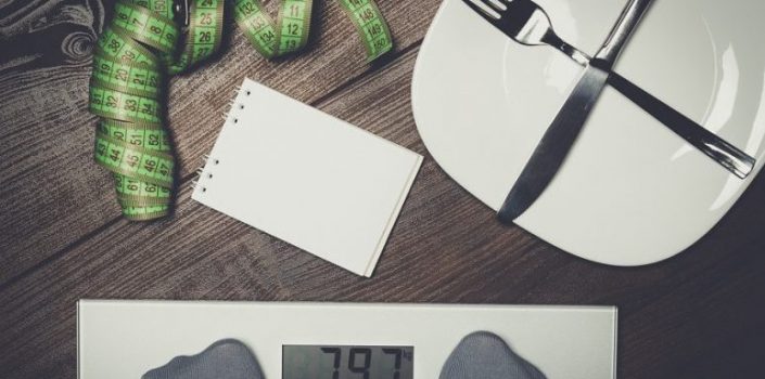Dieting concept with scales on the wooden floor